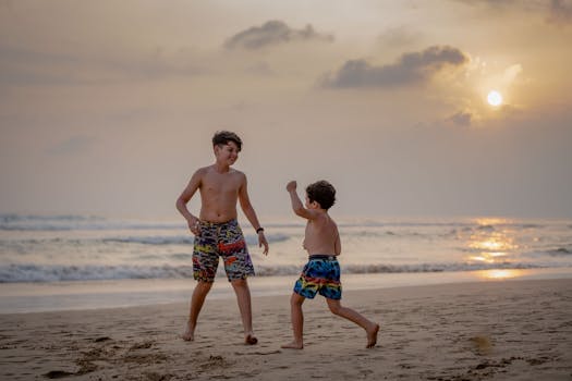 Two boys enjoy a playful moment on a scenic beach in Sri Lanka during sunset.